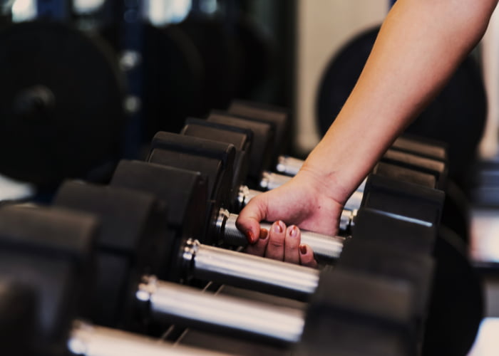 GYM Close-up of a person picking up a dumbbell from a weight rack