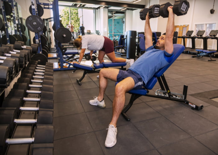GYM Man lifting dumbbells on a bench in the gym