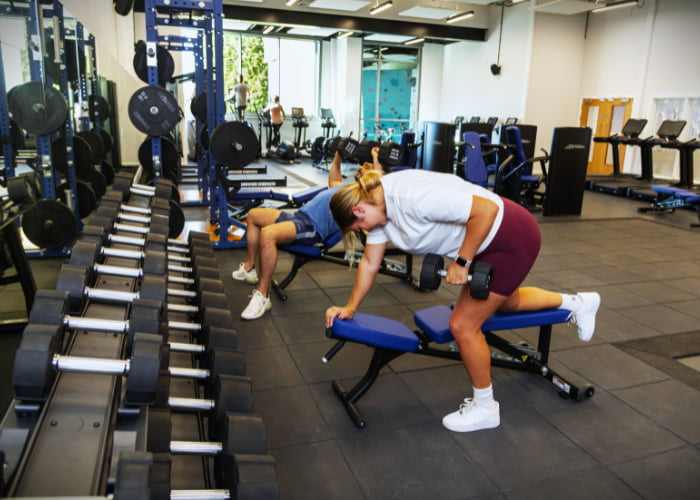 GYM People using dumbbells on benches in the gym